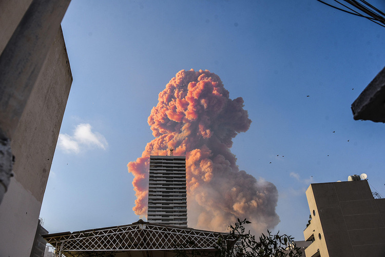 A large plume of smoke can be seen behind a building reaching into the air