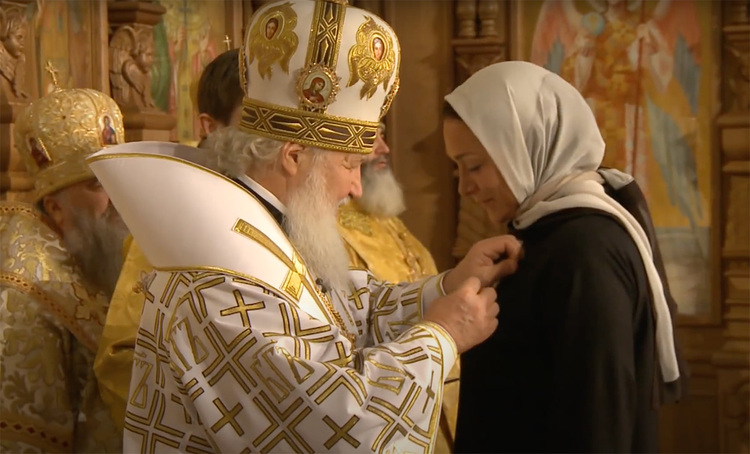 Polyakova is shown receiving an award from Patriarch Kirill