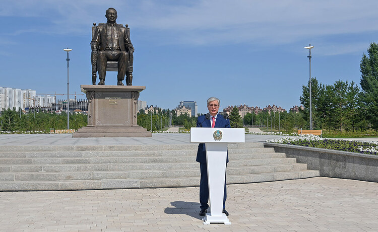 Tokayev stands at a podium in front of a monument