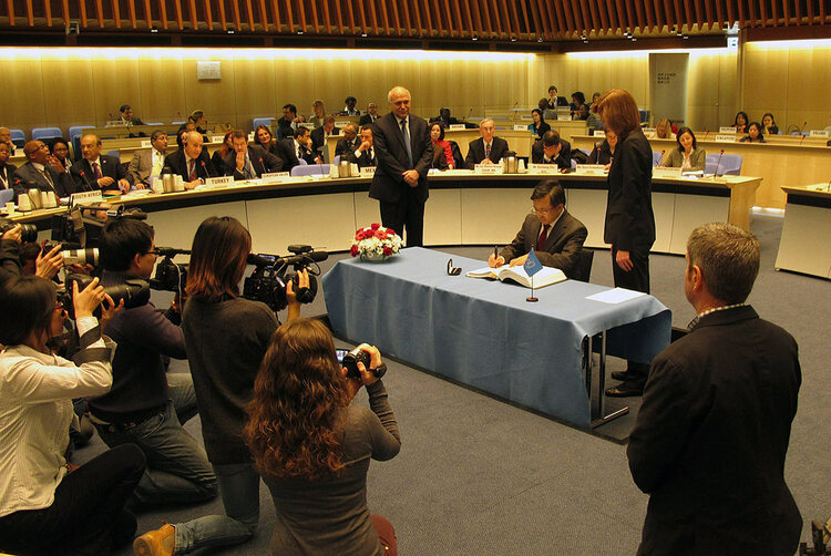 A man signs a treaty while others look on