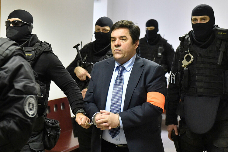Heavily armed members of the Slovak Prison Service bring Marian Kočner into a courtroom