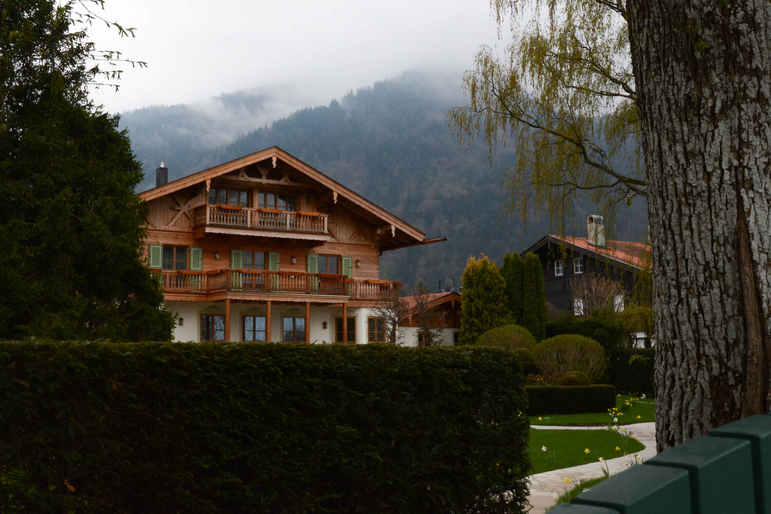 Een groot houten chalet ligt in een mistige bergvallei