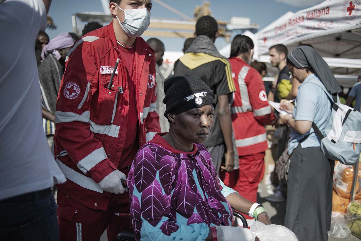 An exhausted asylum seeker pushed in a wheelchair at the port in Palermo (Photo: Valentino Bellini)