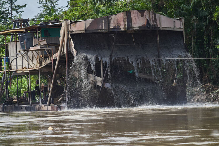 A large dredger in the river, with water and mud pouring out the front