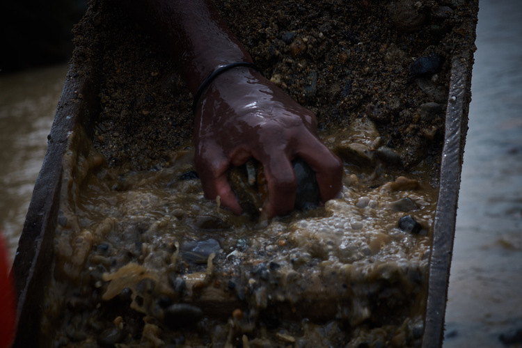 A hand sorts through dirt looking for gold