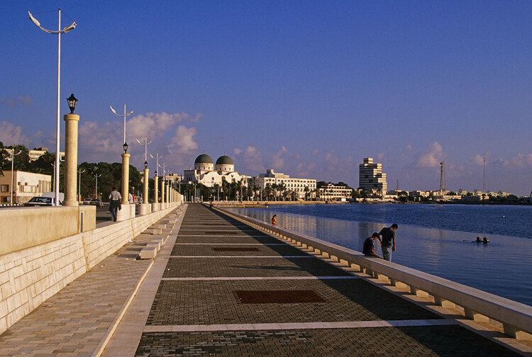 People walk along a wide path next to a waterfront