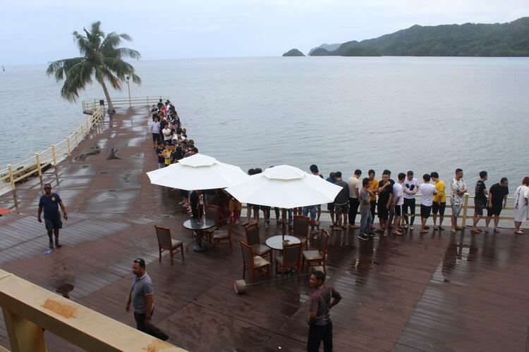 Photo of a deck next to the ocean and several employees lined up against the barrier.