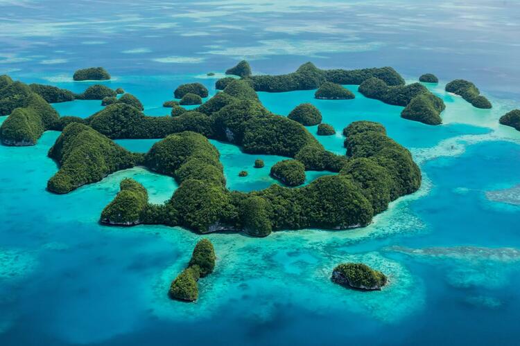 An aerial photograph of islands covered in lush green forest in a turquoise ocean.