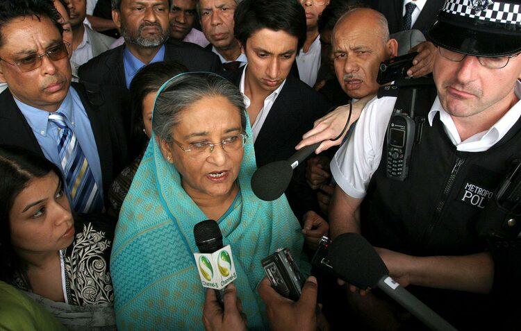 Miah stands next to Sheikh Hasina at London's Heathrow Airport
