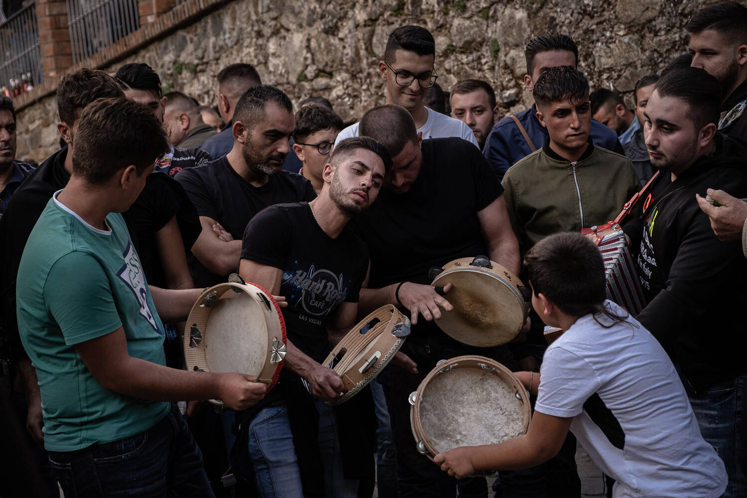 A group of young men play tambarines and dance.