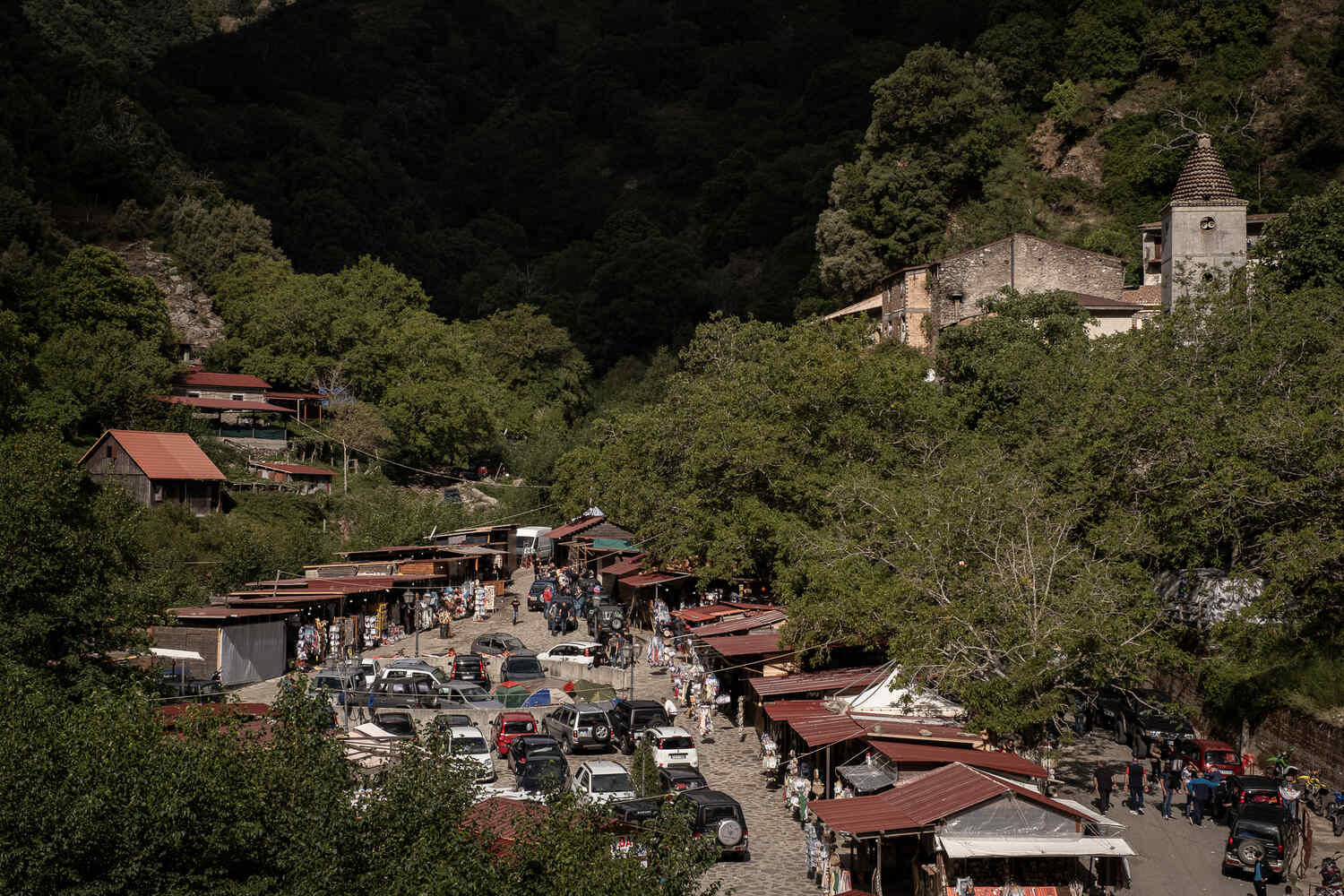 Stone buildings and an old church tower can be seen in the distance, in the foreground, a long street of small make-shift stalls stretches to the horizon.