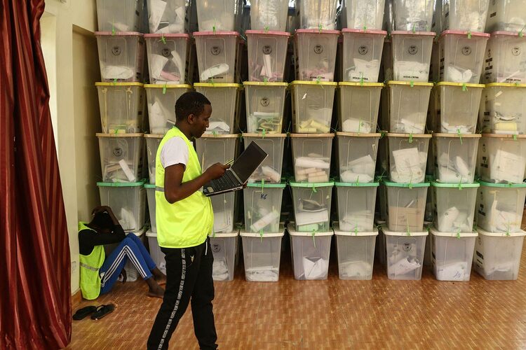An election official walks by stacks of ballot boxes