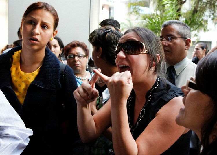 Bank employees and customers seen outside a branch of Banco Canarias in Caracas