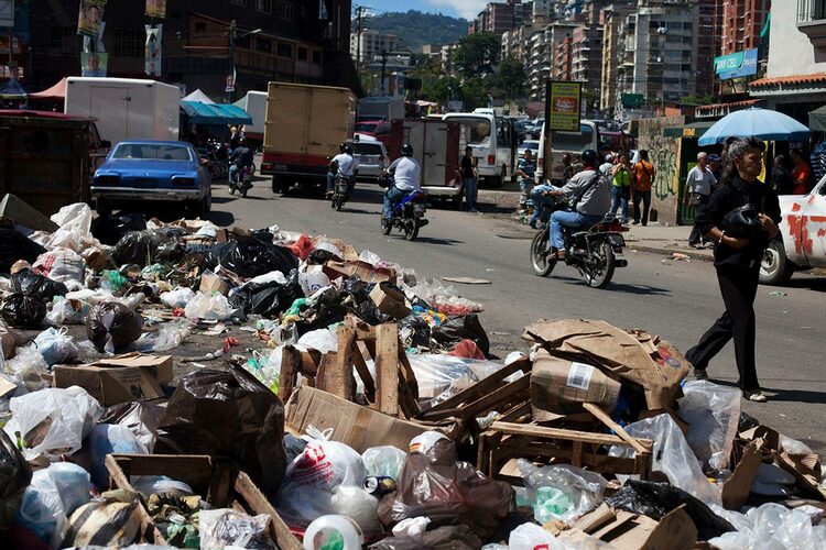 A woman walks past a pile of garbage in Caracas
