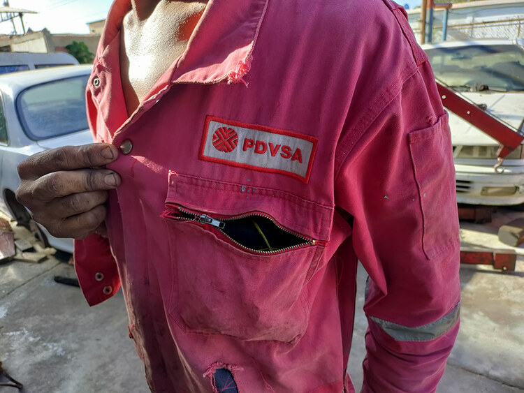 A PDVSA worker shows off his overalls
