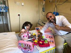 Rodwan sits next to a sick Libyan girl in hospital