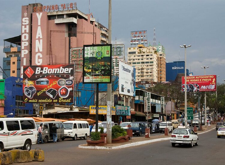 A towndown area with buildings, advertisements and vechiles
