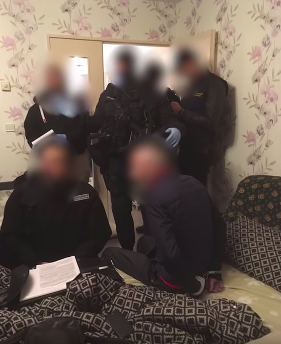Authorities and suspects crowd a room in one of the searched apartments in France. (From: Georgian Police)